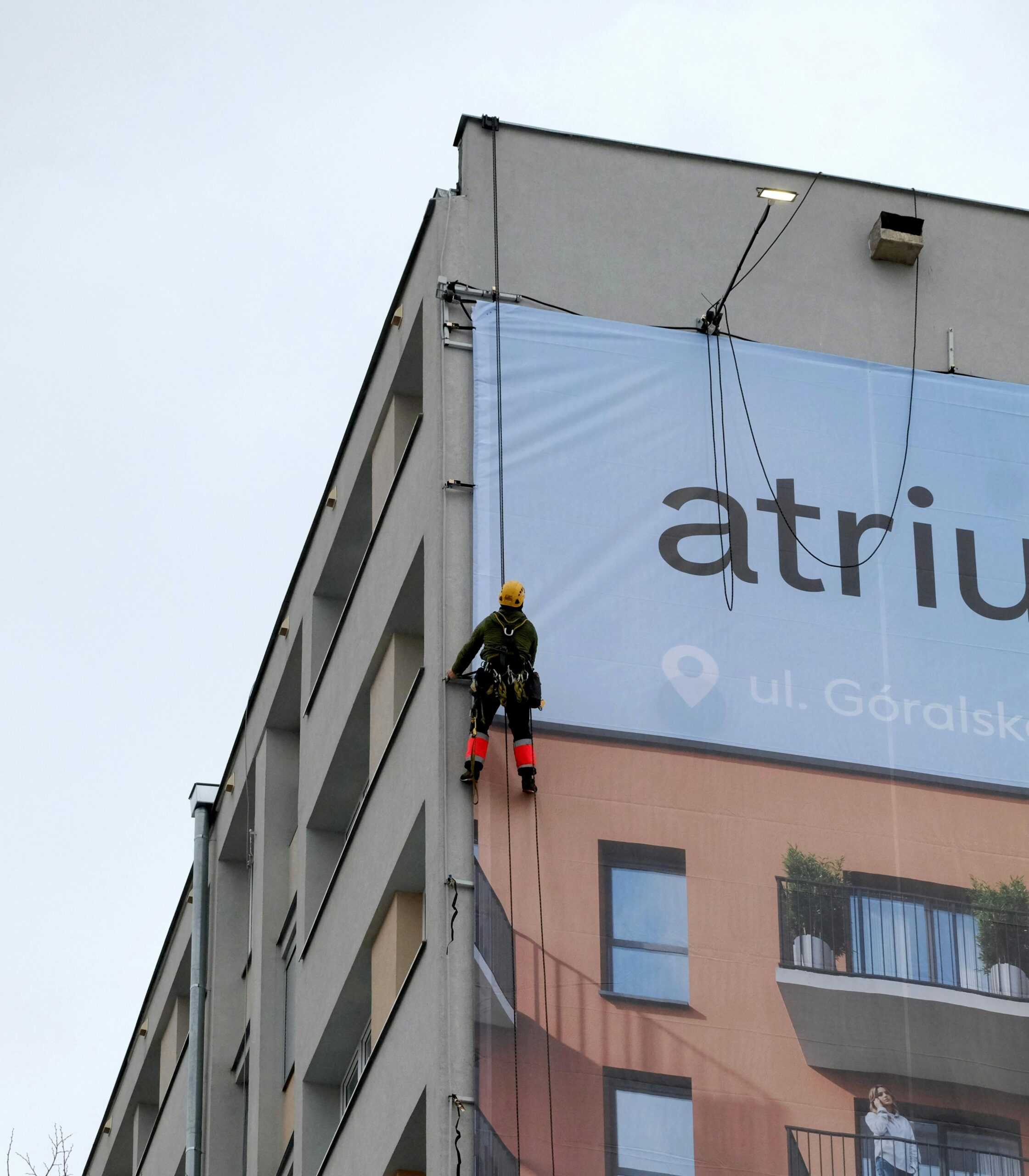 Worker installing a large advertising banner on a building facade