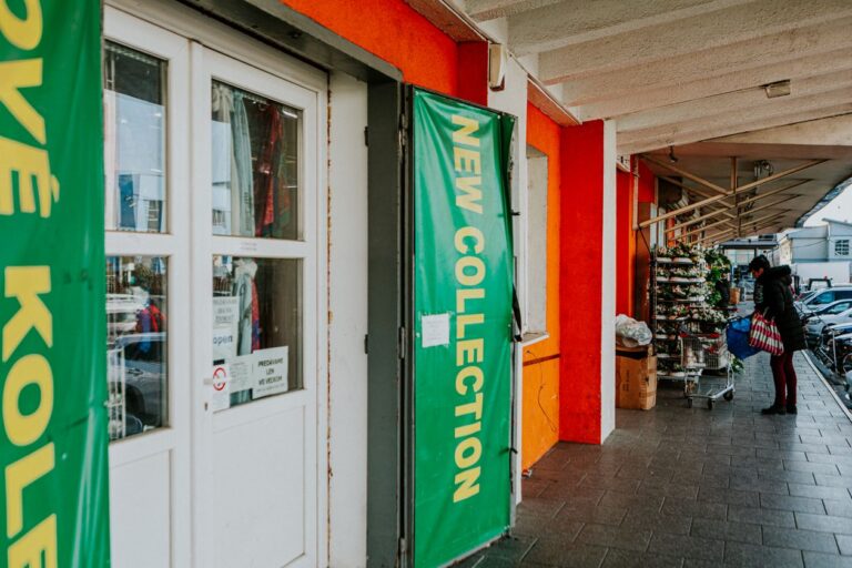 Urban shopping street with retail storefront displaying new collection window signage