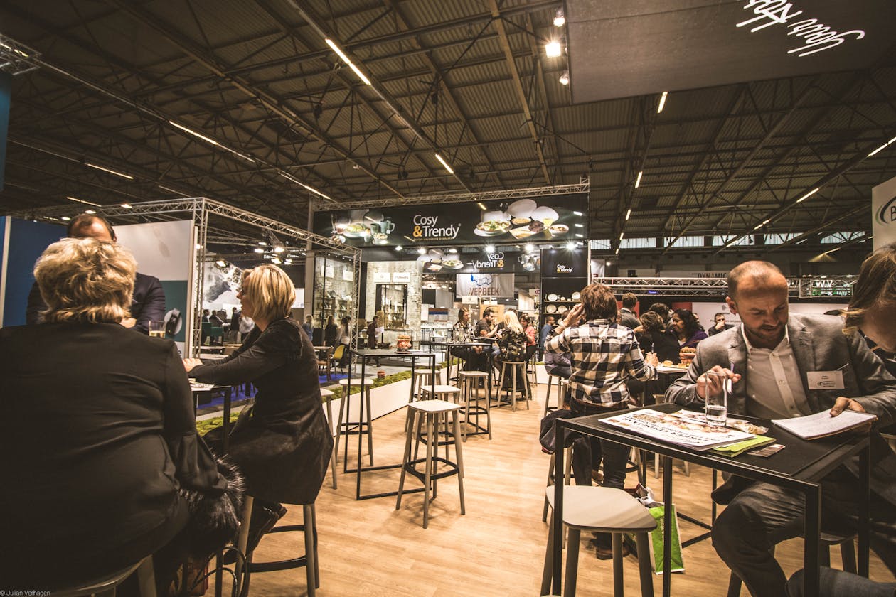 Professionals networking and presenting at display booths at an indoor business expo or trade show