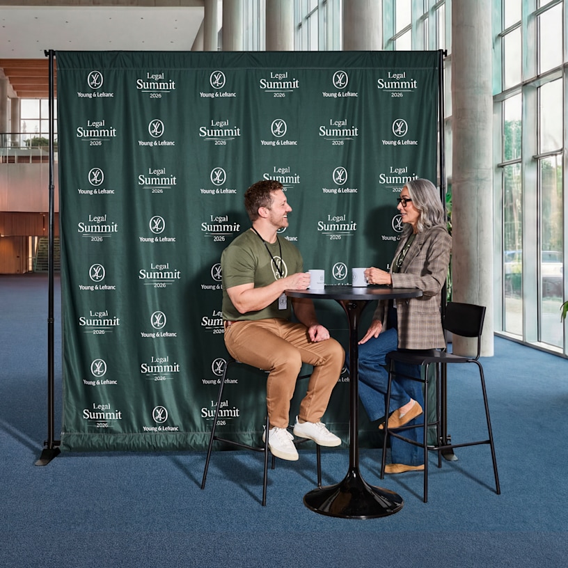 Step and repeat branded event backdrop with people networking at a corporate event