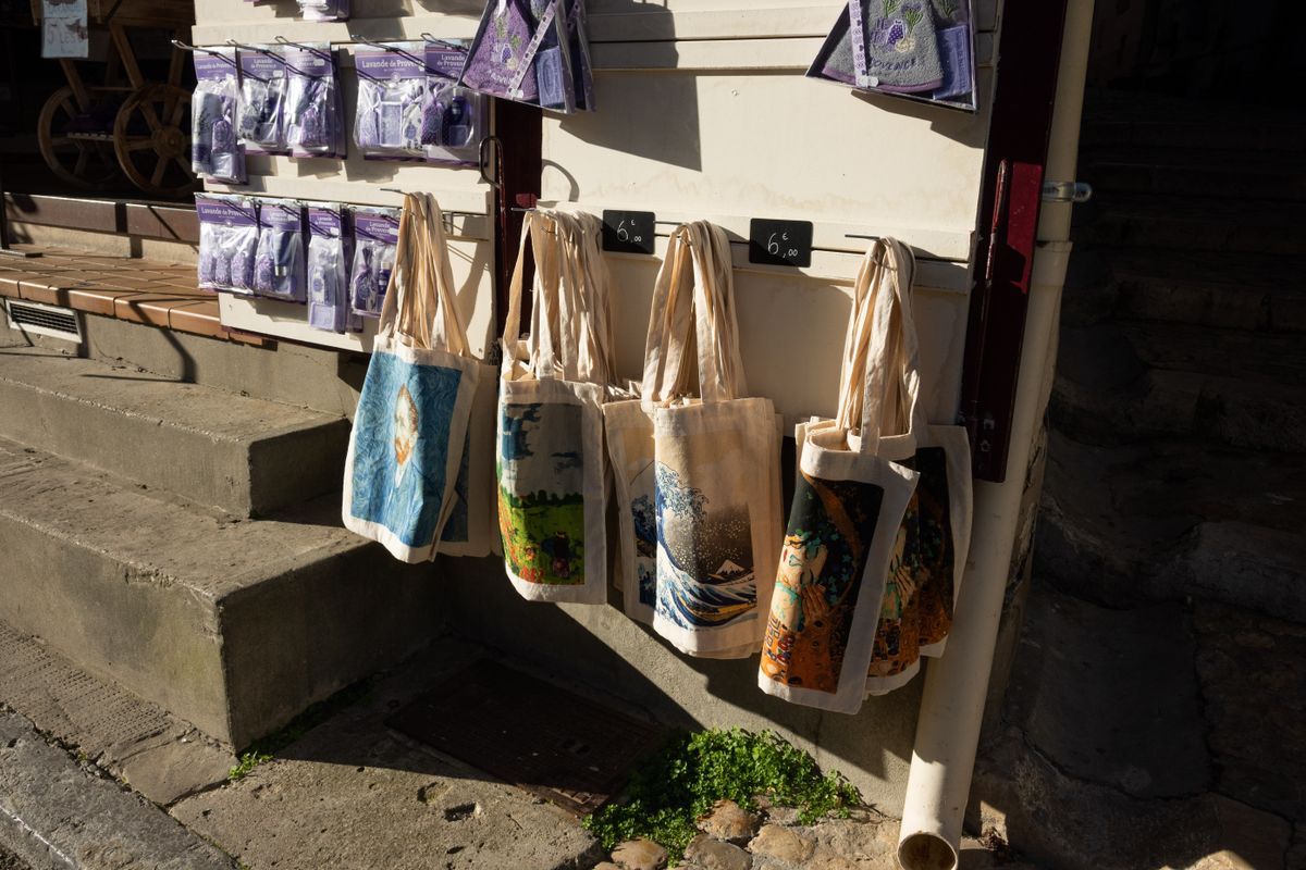 Printed canvas tote bags with artwork designs on display outside a shop
