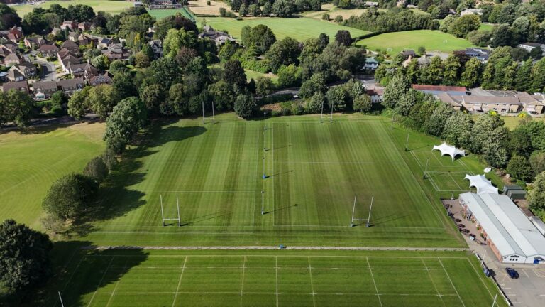 Aerial view of rugby fields surrounded by trees and houses
