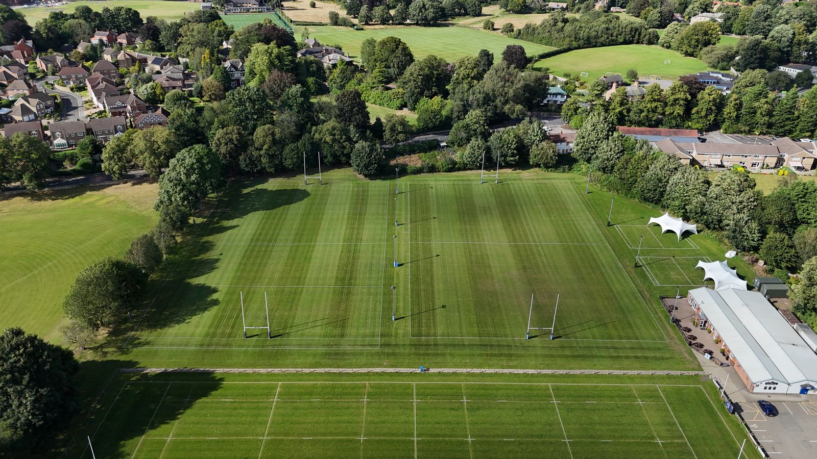Aerial view of rugby fields surrounded by trees and houses