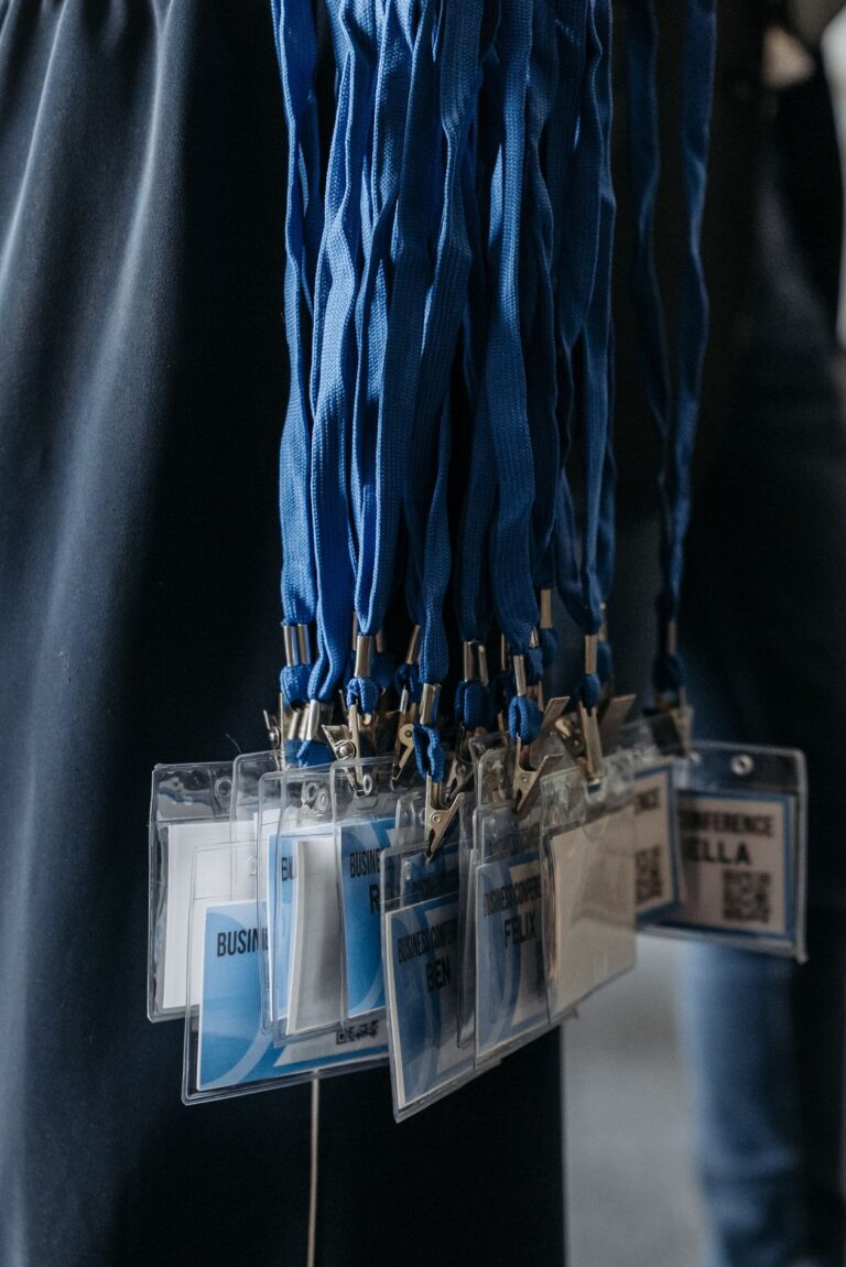 Rows of blue conference lanyards with attendee badges hanging ready for collection