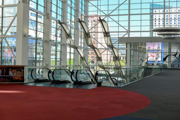 Modern convention centre atrium with glass walls, escalators and a bold red floor graphic