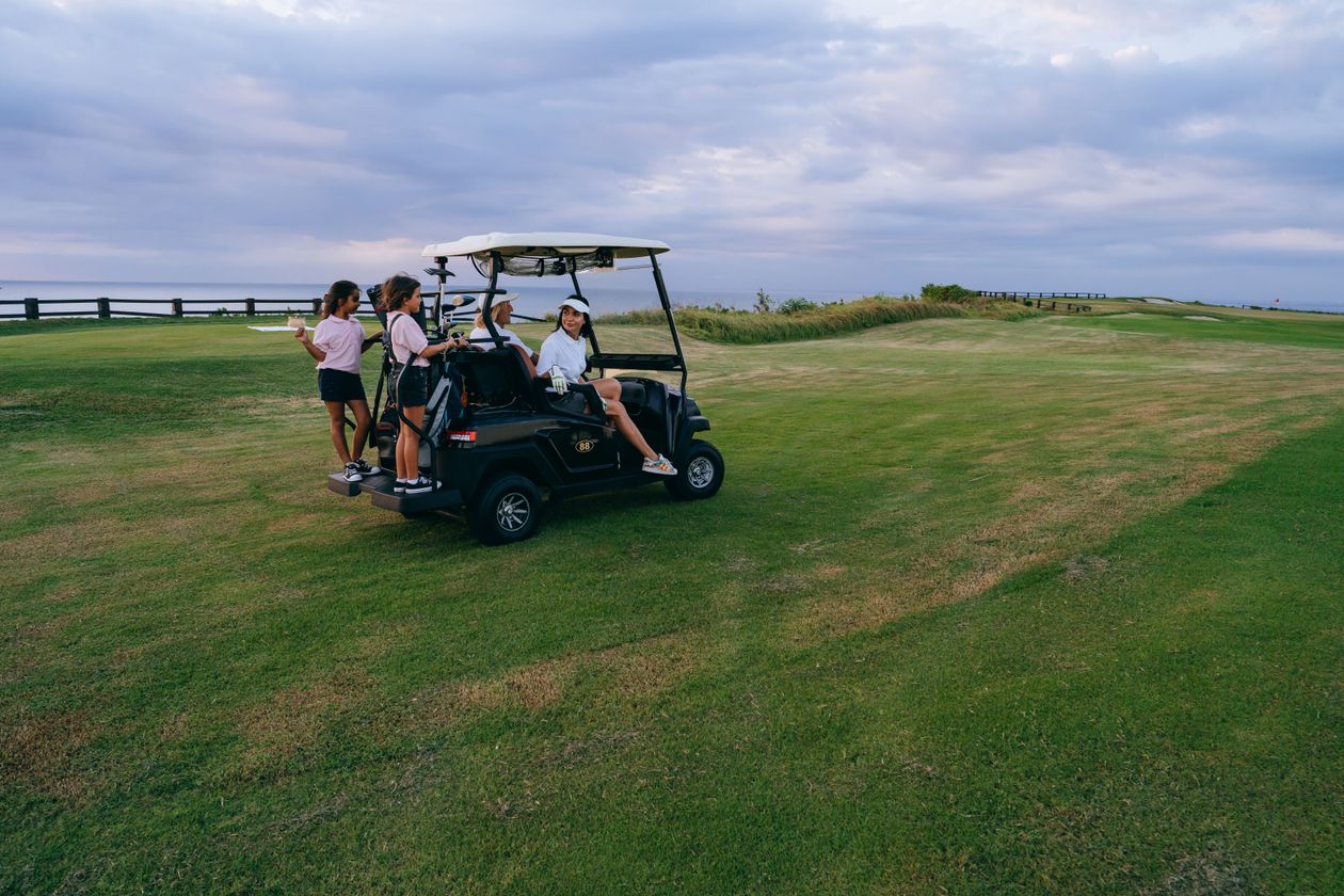 Family riding a golf cart on the course beside the fairway