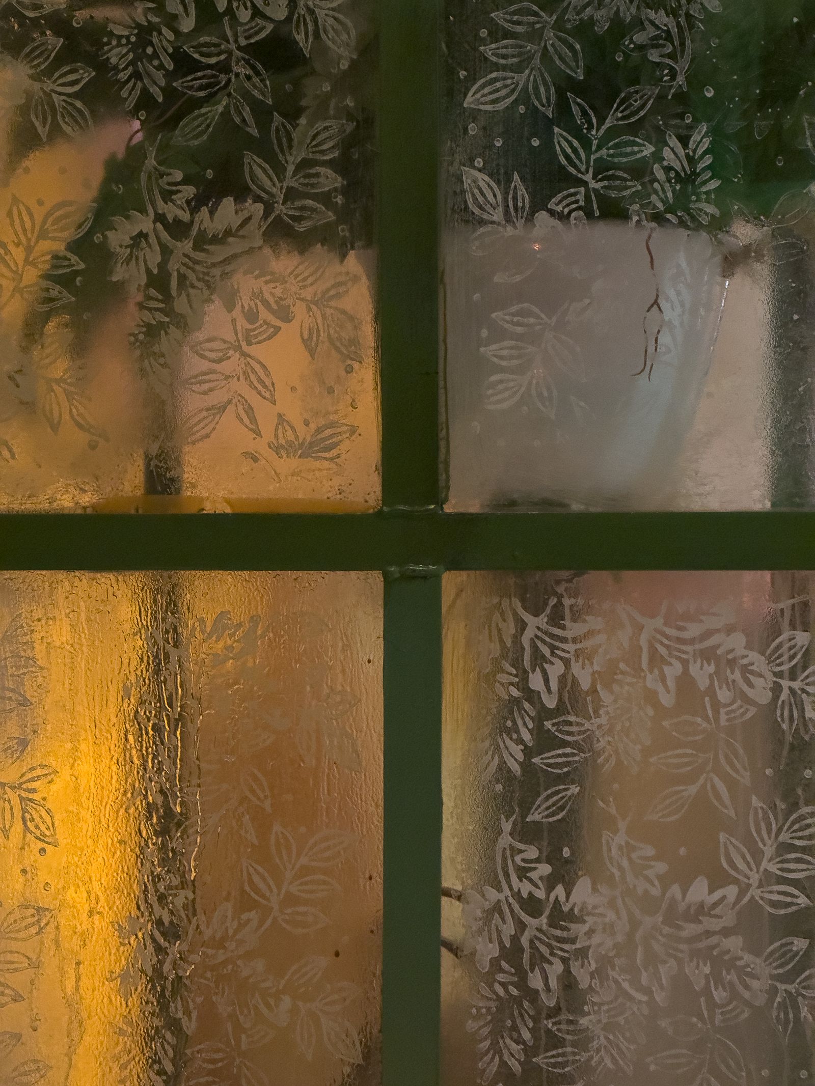 Frosted glass window with a leaf pattern and warm light glowing through
