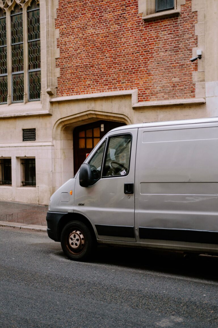 Grey panel van parked beside a brick building