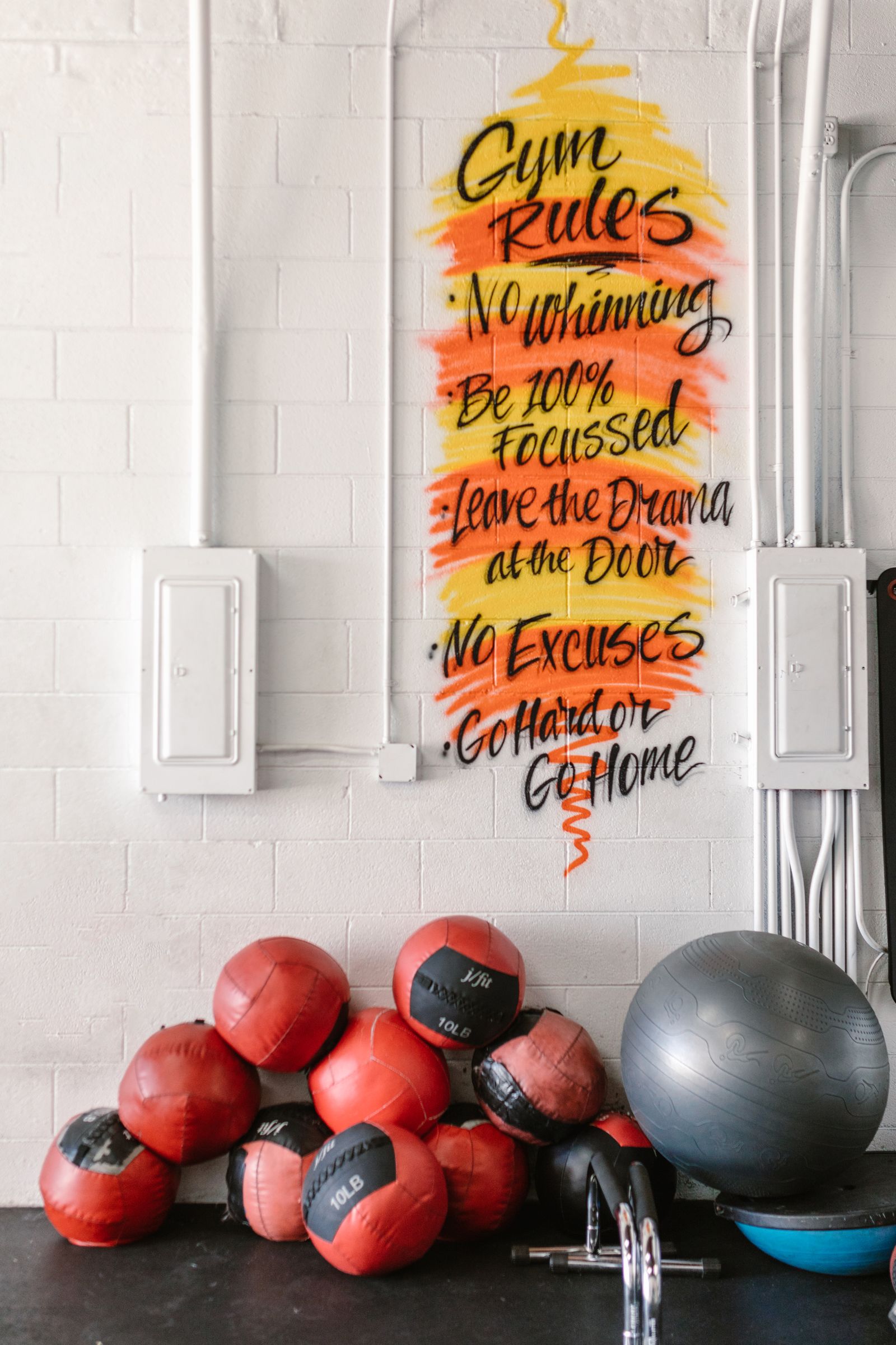 Gym Rules motivational wall graphic above medicine balls