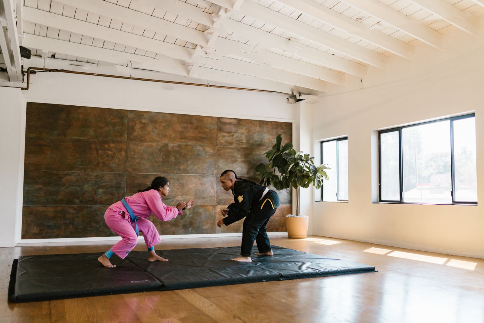 Martial artists training on a mat in a bright studio