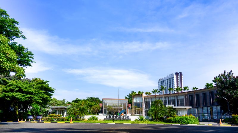 Modern clubhouse building exterior surrounded by greenery