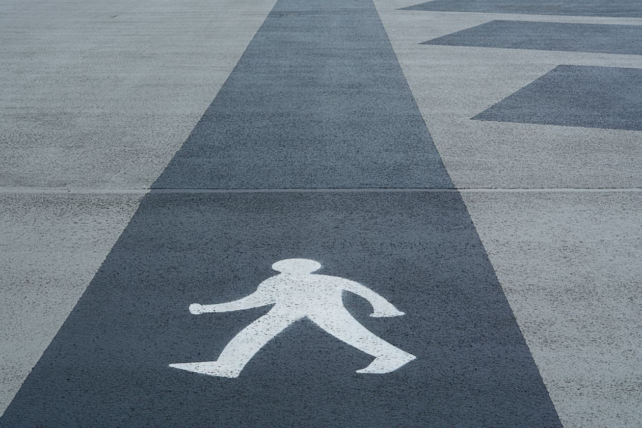 Pedestrian crossing symbol printed on concrete pathway