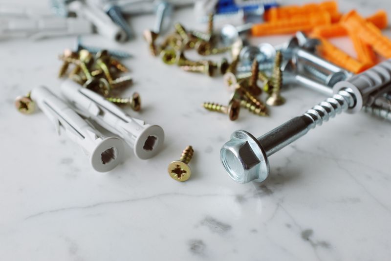 Close-up of assorted screws and wall plugs on a marble surface