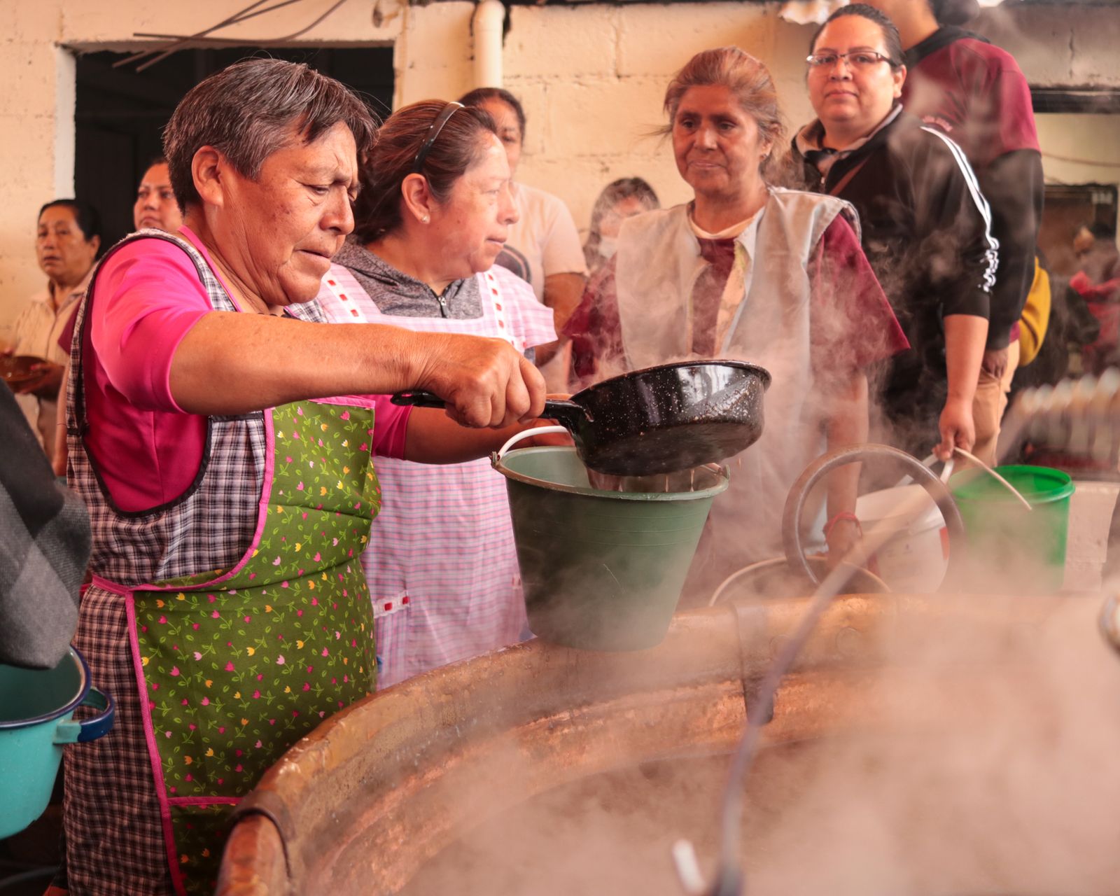 Community kitchen volunteer pouring soup from a large pan
