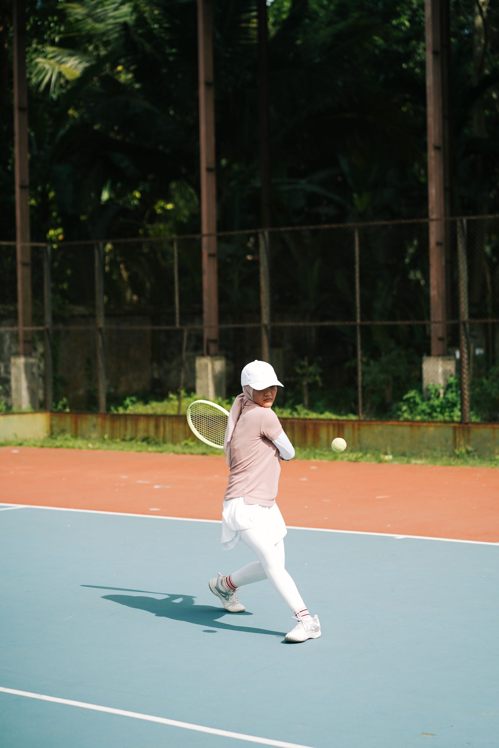 Tennis player in plain kit hitting a backhand on an outdoor court