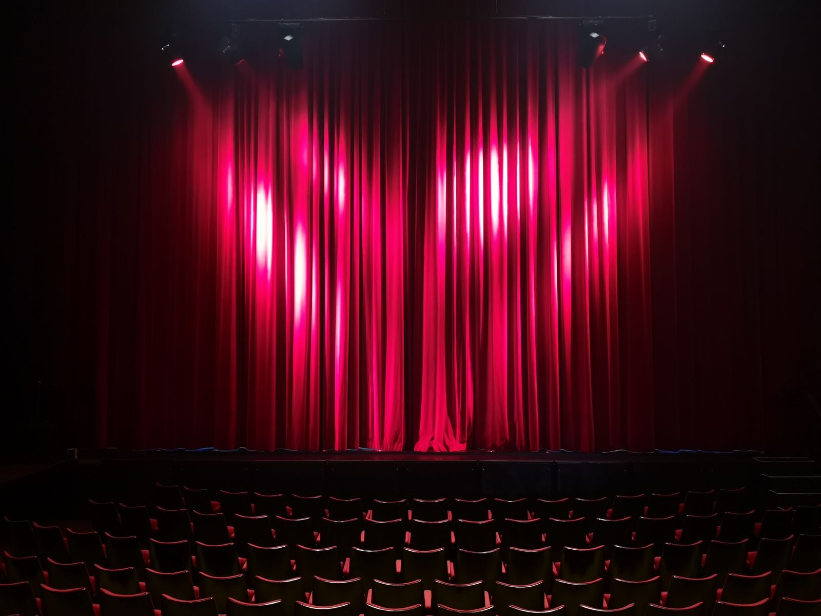 Red theatre curtains and seating in an empty auditorium