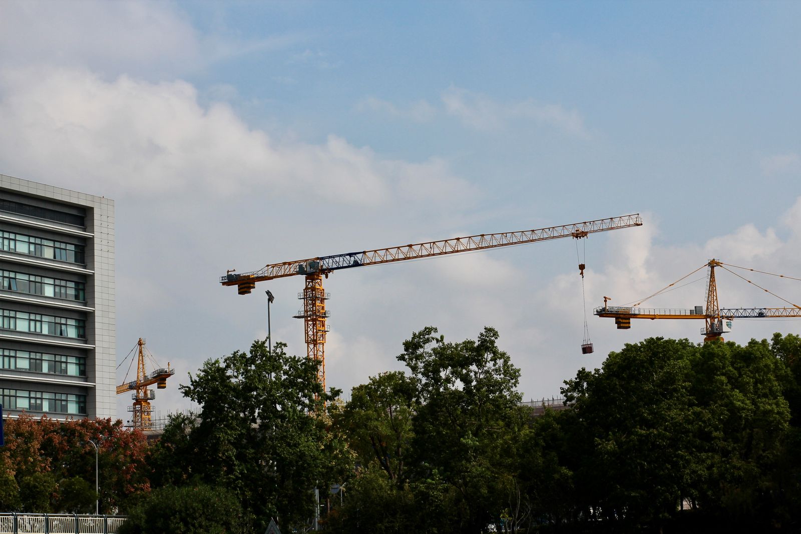Tower cranes and a building under construction against a clear blue sky
