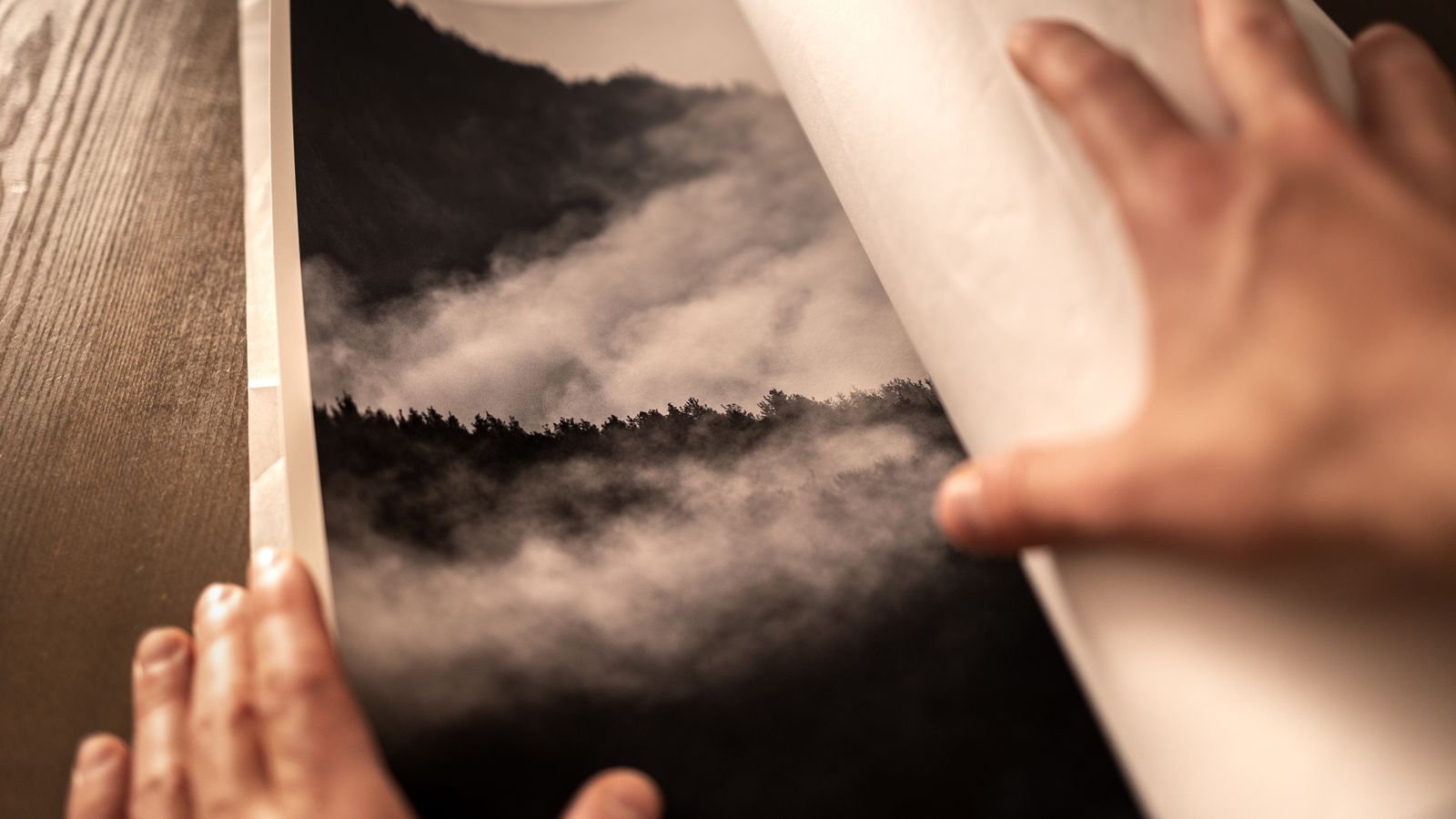 Close-up of hands unwrapping a large photo print
