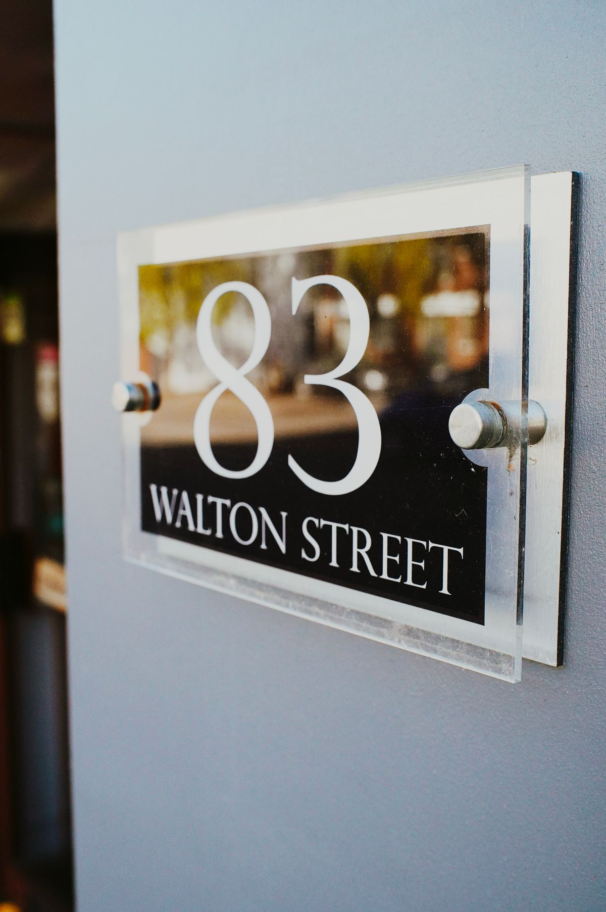Acrylic house number plaque mounted on a wall with standoff fixings
