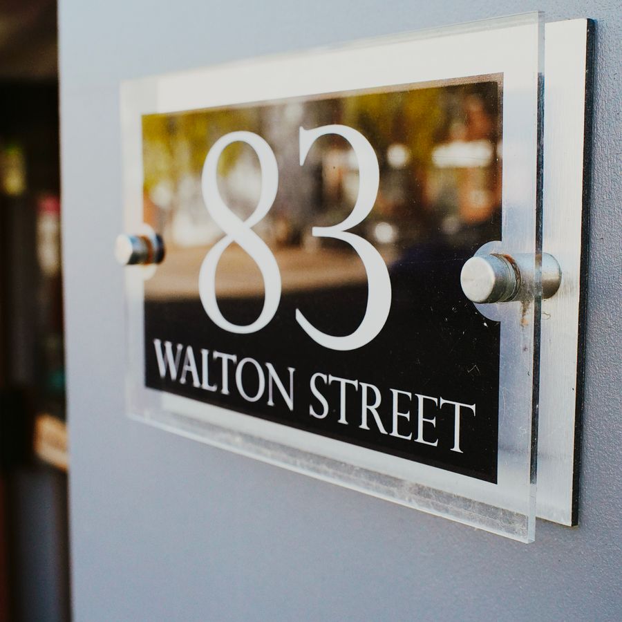 Acrylic house number plaque mounted on a wall with standoff fixings