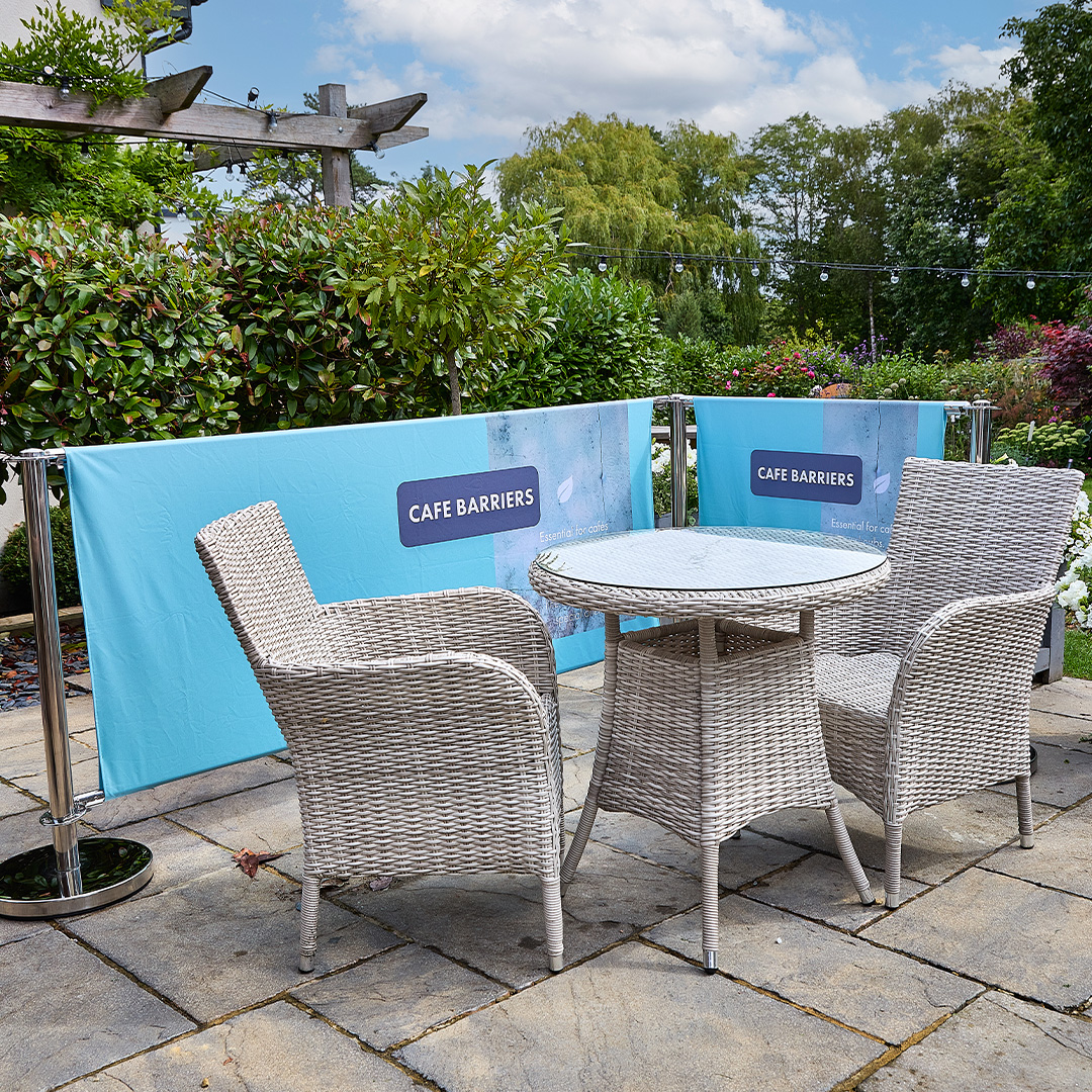 Chrome cafe barrier system with printed fabric panels around outdoor rattan seating