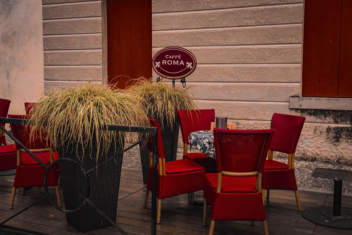 Cafe terrace seating with red chairs and planters marking the boundary