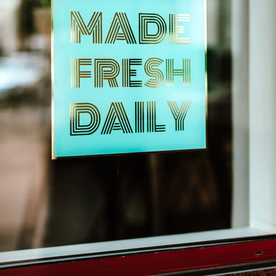 Turquoise and gold vinyl lettering reading 'Made Fresh Daily' on a shop window